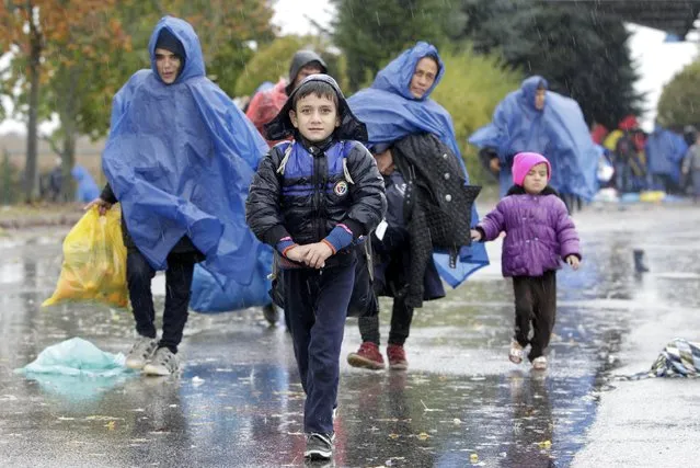 A child looks on as migrants walk into Slovenia from Trnovec, Croatia, October 19, 2015. Some 5,000 migrants reached Slovenia on Monday from Croatia, with another 1,200 on their way by train, the Slovenian interior ministry said, accusing Croatia of ignoring efforts to contain the flow. (Photo by Srdjan Zivulovic/Reuters)
