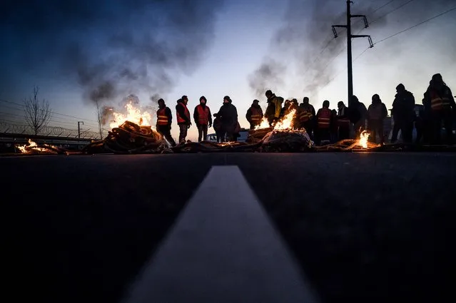 Dozens of unionists block a road with a fire in front of the Total Energies refinery during an action called by the French union General Confederation of Labour (CGT) against a deeply unpopular pensions overhaul in Donges, Western France on February 8, 2023. France braced on February 7, 2023 for new strikes and mass demonstrations against French President's proposal to reform French pensions, including hiking the retirement age from 62 to 64 and increasing the number of years people must make contributions for a full pension. (Photo by Loic Venance/AFP Photo)
