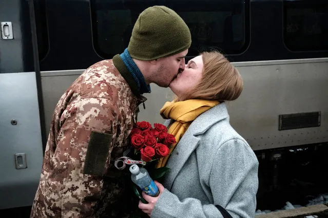 Ukrainian serviceman Maksym kisses his wife Anna as he welcomes her with flowers upon her arrival from Kyiv at the train station in Kramatorsk on Valentines Day on February 14, 2023, amid the Russian invasion of Ukraine. (Photo by Yasuyoshi Chiba/AFP Photo)