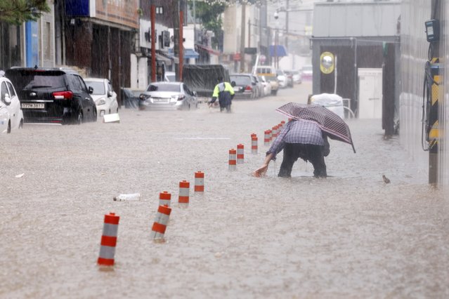 People wade through an inundated street due to heavy rain in Gwangju, South Korea, Thursday, July 17, 2025. (Photo by Jeong Da-eum/Yonhap via AP Photo)