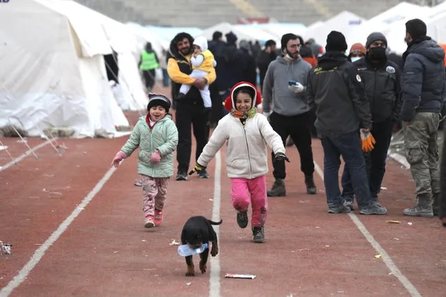 Children play with a dog along an all-weather running track at an AFAD makeshift camp erected in a stadium in the city of Kahramanmaras, southeastern Turkey, 10 February 2023. More than 22,000 people have died and thousands more were injured after two major earthquakes struck southern Turkey and northern Syria on 06 February. Authorities fear the death toll will keep climbing as rescuers look for survivors across the region. (Photo by Abir Sultan/EPA/EFE/Rex Features/Shutterstock)