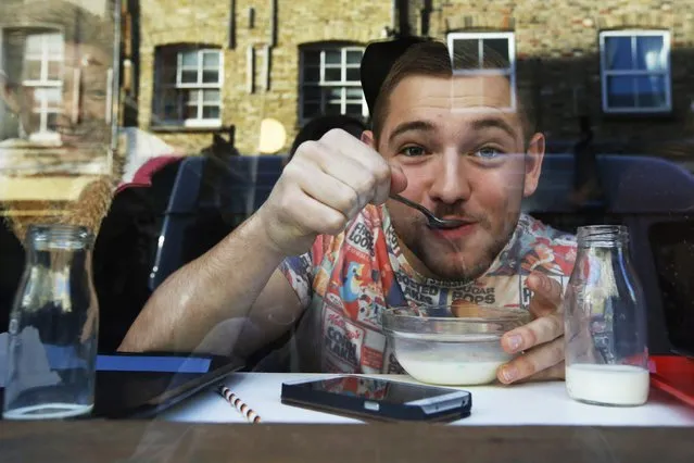 Customer Alex Cuff is seen through the window as he eats cereal at the “Cereal Killer Cafe” in east London December 10, 2014. Identical twin brothers hope they have ticked the right boxes, and ordered in the right flavours, for their new “Cereal Killer Cafe” in London serving only cereal, with toppings and milk. (Photo by Luke MacGregor/Reuters)