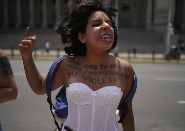 A woman, her chest marked with a message that reads in Spanish: “Just because I am your wife does not mean you can rape me!”,  participates in a march marking International Women's Day, in Lima, Peru, Wednesday, March 8, 2023. (Photo by Martin Mejia/AP Photo)