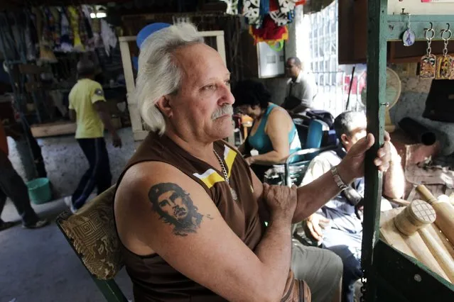 Cuban Oscar Martinez sports a tattoo of late revolutionary hero Ernesto “Che” Guevara while sitting at his street stall in Havana December 17, 2014. (Photo by Reuters/Stringer)