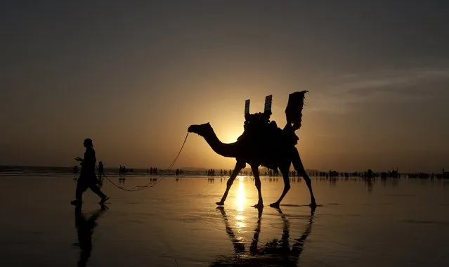 A Pakistani camel owner looks for customers as people visit Karachi beach suffering from warm weather, Friday, October 2, 2015 in Pakistan. (Photo by Shakil Adil/AP Photo)