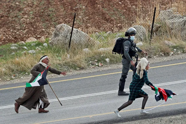 A Palestinian demonstrator runs after an Israeli settler who takes away Palestinian flags during a protest against Jewish settlements, in Kafr Malik in the Israeli-occupied West Bank on November 20, 2020. (Photo by Mohamad Torokman/Reuters)