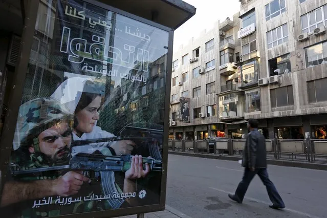 A man walks near an advertisement calling on people to join the Syrian military forces, in Damascus, Syria November 12, 2015. The text on the billboard reads in Arabic: "Our army means all of us, join the armed forces". (Photo by Omar Sanadiki/Reuters)
