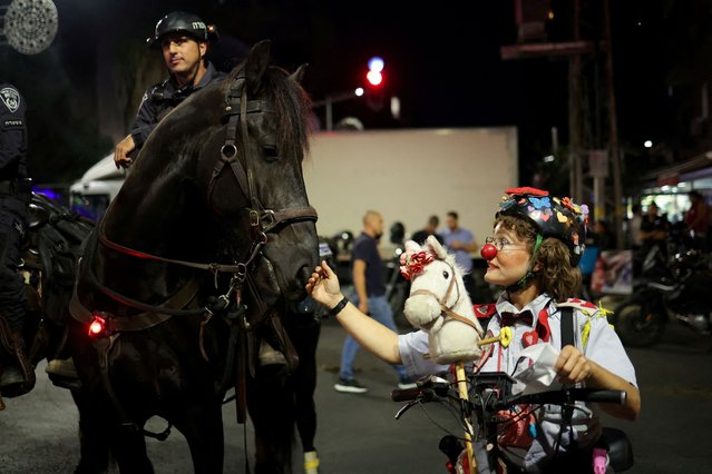 A protester in costume touches a police horse during a demonstration against Israeli Prime Minister Benjamin Netanyahu's government, near the Knesset, the Israeli parliament, in Jerusalem on June 17, 2024. (Photo by Marko Djurica/Reuters)