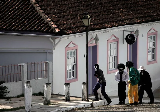 Masked boys walk to the “Cavalhadas” festival in Pirenopolis, Brazil, Sunday, May 19, 2013. The popular festival is a tradition that was introduced in the 1800's by a Portuguese priest to mark the the ascension of Christ. The 3-day festival reenacts the Christian knights' medieval defeat of the Moors. (Photo by Eraldo Peres/AP Photo)