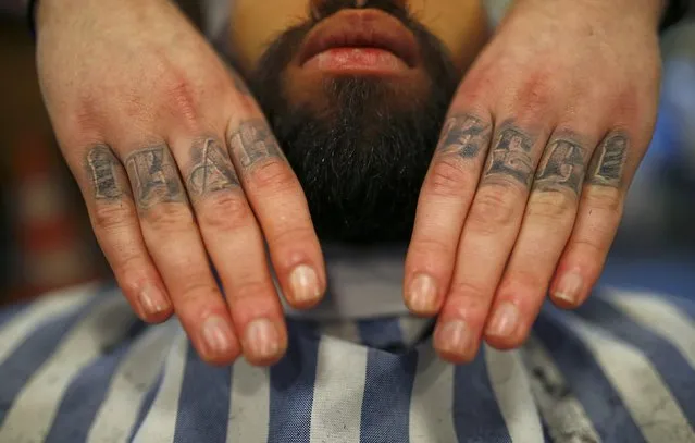 Alex “Torreto” Vellios, a 26-year old barber displays his tattoo reading "barber" as he massages a conditioning oil into the beard of his assistant Sam at his Torreto barber shop in Frankfurt January 6, 2015. (Photo by Kai Pfaffenbach/Reuters)