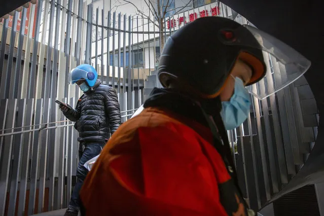 Delivery drivers wearing face masks to protect against the coronavirus walk along a staircase at an office and shopping complex in Beijing, Wednesday, January 6, 2021. China's Hebei province is enforcing stricter control measures following a further rise in coronavirus cases in the province, which is adjacent to the capital Beijing and is due to host events for next year's Winter Olympics. (Photo by Mark Schiefelbein/AP Photo)