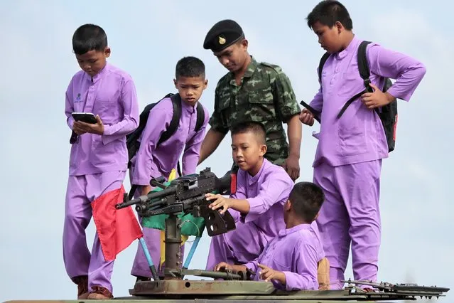Children are shown weapons by a soldier ahead of the country's traditional Children's Day in the southern province of Pattani January 9, 2015. Thailand celebrates Children's Day on the second Saturday of January by organising special events and activities including visits to government offices and army bases for children and youths. (Photo by Surapan Boonthanom/Reuters)