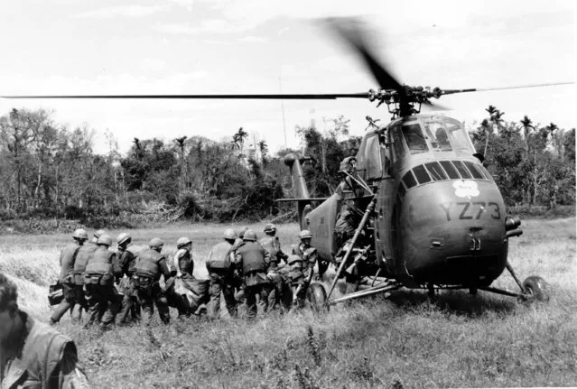 U.S. Marines and Navy Corpsmen line up to load casualties aboard H 34 Marine helicopter at Con Thien, just below the demilitarized zone, in Vietnam on May 17, 1967 during the Vietnam War. (Photo by AP Photo)