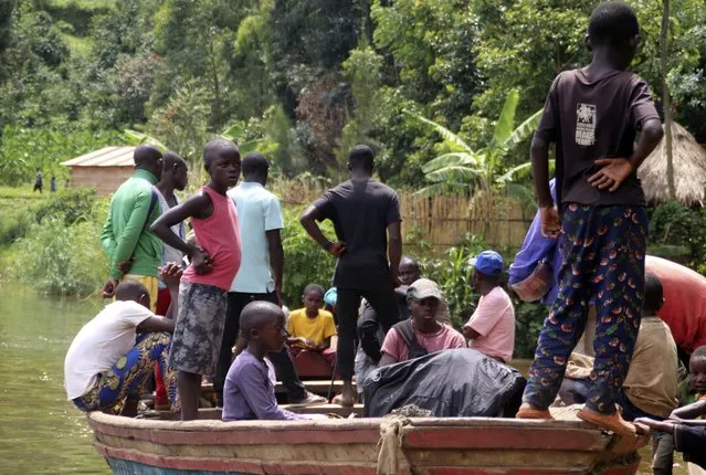 Children gather around a wooden boat conveying two bodies, in Mukwija in Eastern Congo, Wednesday January 6, 2021. Authorities in eastern Congo fear more than 40 people are dead after a motorized wooden boat capsized on Lake Kivu overnight, officials said Wednesday. (Photo by Justin Kabumba/AP Photo)
