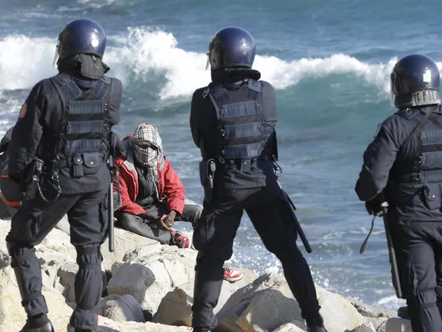 This September 30, 2015 photo shows a migrant facing Italian police officers in riot gear after the evacuation of a tent camp at the Franco-Italian border in Ventimiglia, Italy. In a report by human rights watchdog Amnesty International published Thursday, November 3, 2016, the organization alleges that Italian police have beaten and abused migrants and unlawfully expelled some, under pressure to implement new European Union rules to process arrivals. (Photo by Lionel Cironneau/AP Photo)