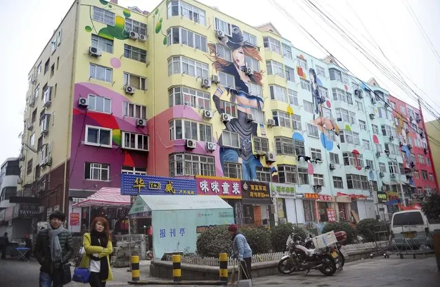 People walk past a building with newly-painted murals along a pedestrian street in Qingdao, Shandong province, January 15, 2015. (Photo by Reuters/China Daily)
