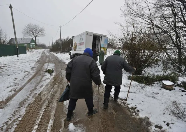 In this Wednesday, November 2, 2016 photo, people approach the shop on wheels in the village of Lyubno, some 90 kilometers (57.5 miles) from Minsk, Belarus. The vans carrying basic foodstuffs are not only a convenient way to purchase everyday goods when the nearest grocery stores are a long journey away, but they are a source of local news, gossip and an opportunity to encounter friends and acquaintances. (Photo by Sergei Grits/AP Photo)