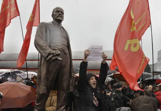 Belarusian opposition activist Dmitry Dashkevich holds a poster and shouts anti-communists slogans in front of the monument to Vladimir Lenin, the founder of Soviet Russia , near the Minsk Tractor Plant in Minsk, Belarus, on Monday, November 7, 2016. The monument had long been on the plant territory, and after the reconstruction shifted to the area outside the plant and opened during the celebration of the 99th anniversary of the 1917 Bolshevik revolution. (Photo by Sergei Grits/AP Photo)
