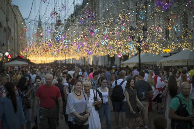 Muscovites, tourists and soccer fans walk through Nikolskaya Street, a favorite meeting place for fans from different countries, during the 2018 soccer World Cup in Moscow, Russia, Saturday, June 23, 2018. (Photo by Alexander Zemlianichenko/AP Photo)