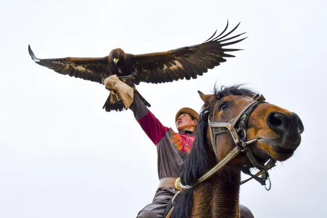 A Kyrgyz man holds a golden eagle for an eagle hunt riding a horse during the hunting festival “Salburun” in Tuura-Suu, a small village nestled among the mountains, about 250 km. (156 miles) south-east of Bishkek, Kyrgyzstan, Tuesday, February 23, 2021. Salburun comes from the nomadic tradition of hunting and protecting herds from predators such as wolves. (Photo by Vladimir Voronin/AP Photo)