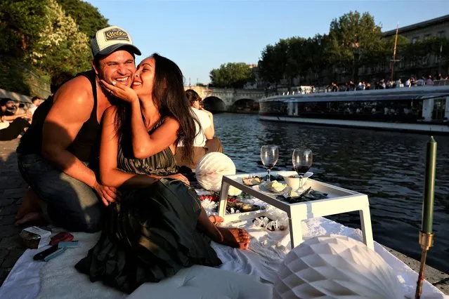 Djamel and Andie enjoy the sunset on a bank of the River Seine, in Paris, France on June 15, 2023. (Photo by Stephanie Lecocq/Reuters)