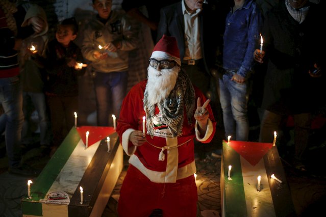 A Palestinian wearing a Santa Claus costume holds a candle during a rally to pay tribute to Palestinians who organizers said were killed recently by Israeli troops, on Christmas day in Gaza City December 25, 2015. (Photo by Suhaib Salem/Reuters)