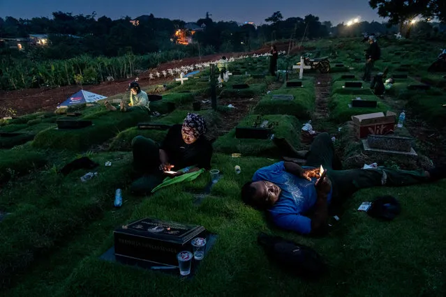 Shortlist, open competition, street photography. Night in Pandemic Time, taken at the Pondok Ranggon Cemetery, Jakarta, late one afternoon. The funeral officers were having a break, watching videos on their smartphones and chatting with their families. (Photo by Ares Jonekson Saragi/Sony World Photography Awards)