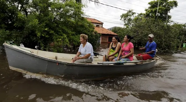 People travel on a boat near flood-affected houses in Asuncion, December 27, 2015. More than 100,000 people have had to evacuate from their homes in the bordering areas of Paraguay, Uruguay, Brazil and Argentina due to severe flooding in the wake of heavy summer rains brought on by El Nino, authorities said on Saturday. (Photo by Jorge Adorno/Reuters)