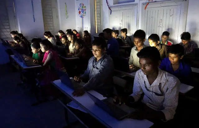Slum students study on their laptops inside an E-classroom at a government run school in Ahmedabad, India, July 25, 2018. (Photo by Amit Dave/Reuters)