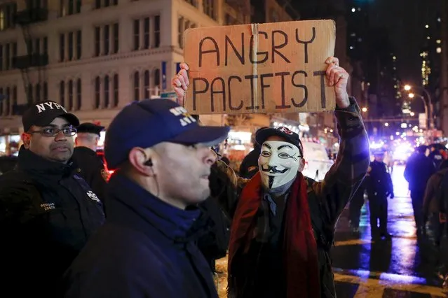 A protester holds up a sign in front of a New York Police officer while people march in a protest against the police in Manhattan, New York, December 28, 2015 after a grand jury cleared two Cleveland police officers on Monday in the November 2014 fatal shooting of 12-year-old Tamir Rice. Rice was brandishing a toy gun in a park, and a prosecutor said there were a series of mistakes but no criminal activity. (Photo by Eduardo Munoz/Reuters)