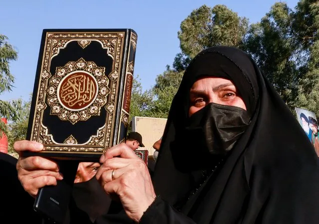 A woman holds a copy of the Koran during a protest against a man who tore up and burned a copy of the Koran outside a mosque in the Swedish capital Stockholm, near the Swedish embassy in Baghdad, Iraq on June 30, 2023. (Photo by Thaier Al-Sudani/Reuters)