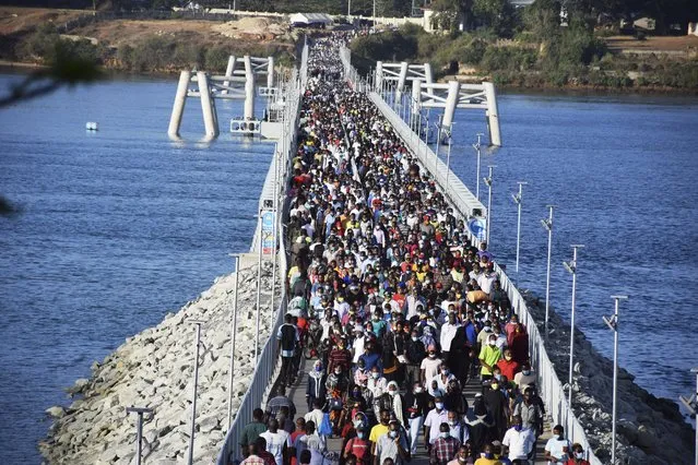 Some hundreds of Mombasa residents cross the recently constructed floating foot bridge from Mombasa's Likoni mainland to the Mombasa Island on Wednesday March 31, 2021. More than three hundred thousand people who normally cross the waterway via Likoni Ferry channel everyday, are now forced to use the floating foot bridge after the Mombasa County Covid-19 committee ordered all people to cross via the bridge. It is not exactly known how many people the floating bridge can sustain and some fear a disaster due to the high number of people crossing through the bridge. (Photo by Gideon Maundu/AP Photo)