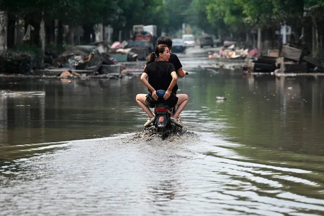Local residents ride a scooter on a flooded street in the aftermath of flooding from heavy rains in Zhuozhou city, in northern China’s Hebei province on August 9, 2023. China's capital has been hit by record downpours in recent weeks, damaging infrastructure and deluging swaths of the city's suburbs and surrounding areas. In Hebei province, which neighbours Beijing, 15 were reported to have died and 22 were missing. (Photo by Jade Gao/AFP Photo)