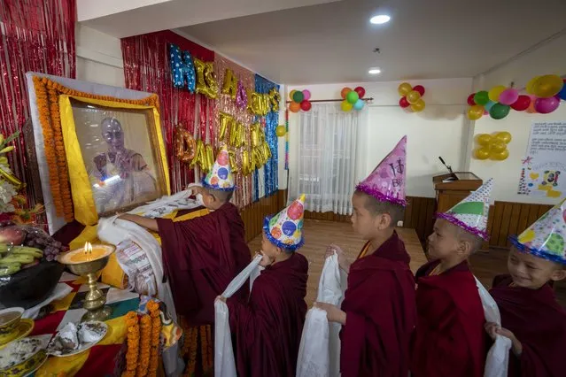Young Buddhist monks hold ceremonial scarves and stand in queue to offer prayers in front of a portrait of their spiritual leader the Dalai Lama during his 88th birthday celebration in Kathmandu, Nepal, Thursday, July 6, 2023. (Photo by Niranjan Shrestha/AP Photo)