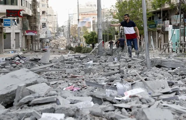 A man inspects the rubble of destroyed commercial building and Gaza health care clinic following an Israeli airstrike on the upper floors of a commercial building near the Health Ministry in Gaza City, on Monday, May 17, 2021. (Photo by Adel Hana/AP Photo)