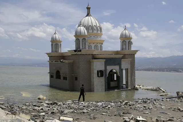A man looks at a mosque that is isolated by water after its bridge was broken due to the massive earthquake and tsunami in Palu, Central Sulawesi, Indonesia Friday, October 5, 2018. French rescuers say they've been unable to find the possible sign of life they detected a day earlier under the rubble of a hotel that collapsed in the earthquake a week ago on Indonesia's Sulawesi island. (Photo by Aaron Favila/AP Photo)