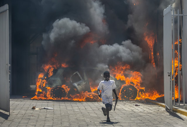 A boy runs out from the Nissan auto dealership set ablaze during a protest by a disgruntled sector of the Haitian police force known as Fantom 509, in Port-au-Prince, Haiti, Wednesday, March 17, 2021. (Photo by Dieu Nalio Chery/AP Photo)