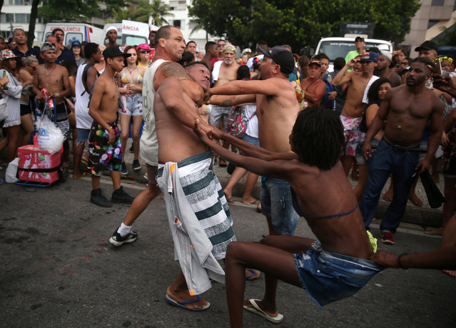 People try to help a man who is being detained for suspecetd robbery during the Gay Pride Parade at Copacabana beach in Rio de Janeiro, Brazil, December 11, 2016. (Photo by Pilar Olivares/Reuters)