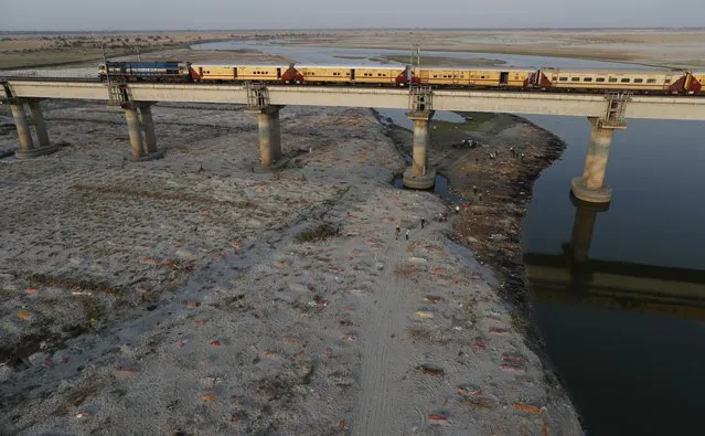 Several bodies are seen buried in shallow graves on the banks of the Ganges River in Prayagraj, India. Saturday, May 15, 2021. Police are reaching out to villagers in northern India to investigate the recovery of bodies buried in shallow sand graves or washing up on the Ganges River banks, prompting speculation on social media that they were the remains of COVID-19 victims. (Photo by Rajesh Kumar Singh/AP Photo)