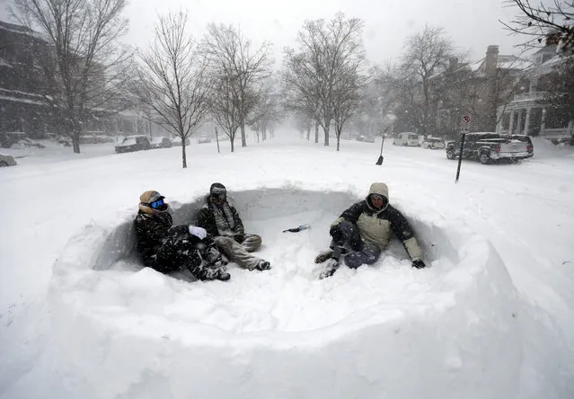 Tyler Ridge, left, Evan Oakes, and Stephen Biggs, relax in a snow fort in the median of Monument Avenue in Richmond, Va., Saturday, January 23, 2016. A massive winter storm buried much of the U.S. East Coast in a foot or more of snow by Saturday, shutting down transit in major cities, stranding drivers on snowbound highways, knocking out power to tens of thousands of people. (Photo by Steve Helber/AP Photo)