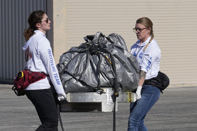 Recovery team members carry a capsule containing NASA's first asteroid samples to a temporary clean room at Dugway Proving Ground in Utah on Sunday, September 24, 2023. The Osiris-Rex spacecraft released the capsule following a seven-year journey to asteroid Bennu and back. (Photo by Rick Bowmer/Pool via AP Photo)