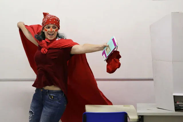 A woman, donning the Workers' Party official colror celebrates after voting in the presidential runoff election in Sao Paulo, Brazil, Sunday, October 28, 2018. Brazilian voters decide who will next lead the world's fifth-largest country, the left-leaning Fernando Haddad of the Workers' Party, or far-right rival Jair Bolsonaro of the Social Liberal Party. (Photo by Nelson Antoine/AP Photo)