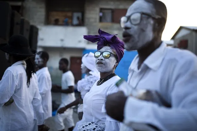 In this November 1, 2018 photo, voodoo believers who are supposed to be possessed with Gede spirit walk in the middle of the street during the annual Voodoo festival Fete Gede at Cite Soleil Cemetery in Port-au-Prince, Haiti. Every year, during the celebration, they paint their faces with white powder, wear the loas' clothes, travel the narrowly pathways through the shanty town and go to cemeteries to pay tribute to the spirits. (Photo by Dieu Nalio Chery/AP Photo)