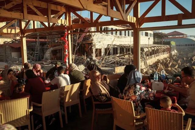 Palestinians sit at a coffee shop terrace at the side of Israeli airstrike in Gaza on May 23, 2021. (Photo by Majdi Fathi/NurPhoto/Rex Features/Shutterstock)