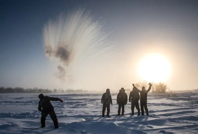 A villager throws hot water into the air while harvesting ice from a local lake near the settlement of Oy, some 70 km south of Yakutsk, with the air temperature at about minus 41 degrees Celsius, on November 27, 2018. Many people in the Sakha (Yakutia) Republic depend on melted water as there is no other way to supply water due to extremely cold winter temperatures in the permafrost-covered region. (Photo by Mladen Antonov/AFP Photo)