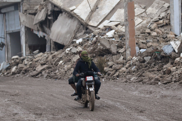 Men ride a motorcycle near damaged buildings in al-Rai town, northern Aleppo countryside, Syria December 30, 2016. (Photo by Khalil Ashawi/Reuters)