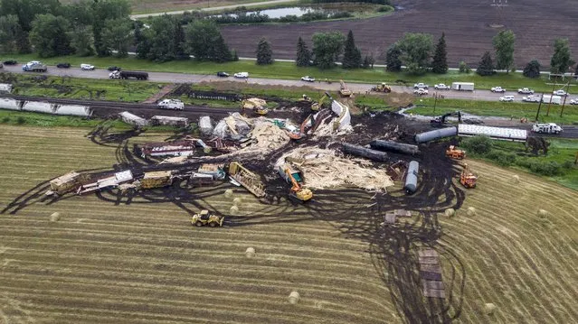 Crews work to clean up a spill after the derailment of a 20-car train carrying “tar sand” and lumber near Blackfalds, Alberta, Canada,  Saturday, July 3, 2021.  (Photo by Jeff McIntosh/The Canadian Press via AP Photo)