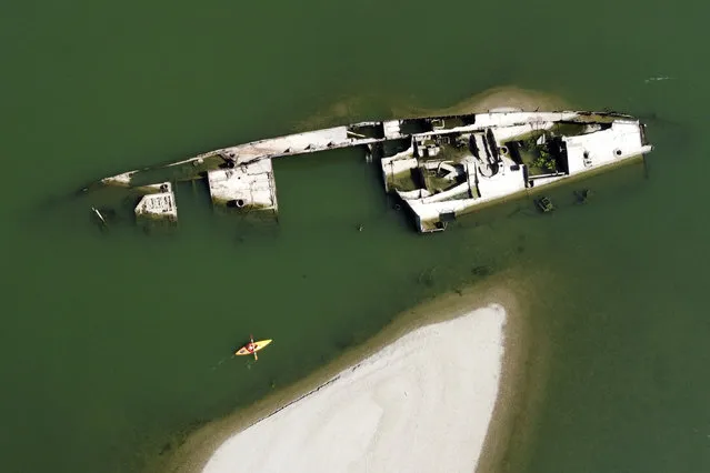 A kayaker paddles by the wreckage of a WWII German warship in the Danube River near Prahovo, Serbia, Friday, August 26, 2022. The hulks of dozens of World War II German battle ships have been exposed on the river near the town of Prahovo after severe drought hit most of Europe this summer. (Photo by Darko Vojinovic/AP Photo)