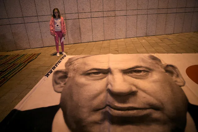 An Israeli girl stands next to a placard with the photo of Israeli Prime Minister Benjamin Netanyahu during a protest against the high cost of living in the centre of Tel Aviv, Israel December 22, 2018. (Photo by Corinna Kern/Reuters)