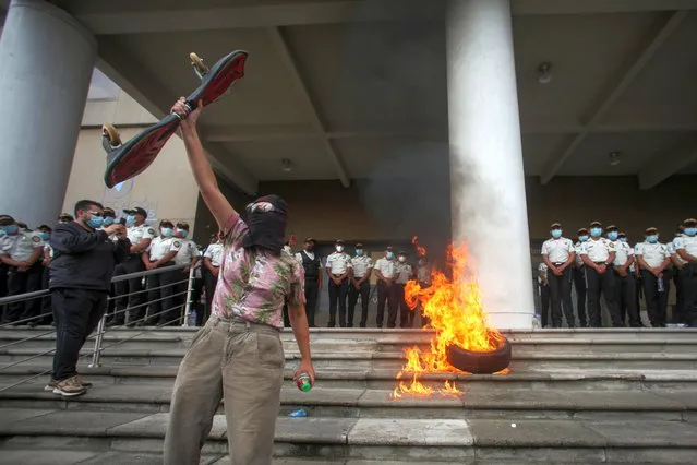 A demonstrator yells in front of burning tires outside the Public Ministry building during a protest to demand the resignation of Guatemalan President Alejandro Giammattei and Attorney General Maria Porras, in Guatemala City, Guatemala on July 29, 2021. (Photo by Sandra Sebastian/Reuters)